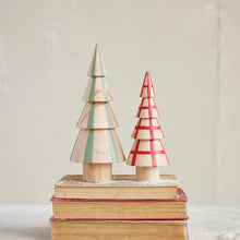 Load image into Gallery viewer, The Hand Painted Wood Tree set features two solid wood trees—one with green stripes, one with red plaid—resting on vintage books dusted with faux snow for a charming accent against any neutral background.