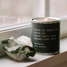 Load image into Gallery viewer, A Legends Candles - Pick From 20 Quotes candle by Lit Decor and Gift, made with soy wax and vegan-friendly, sits lit on a windowsill beside two unpolished crystals—one green, one clear.