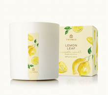 Load image into Gallery viewer, A white Thymes Aromatic 8 oz Candle by Lit Decor and Gift sits beside a watercolor lemon-decorated box, offering an uplifting, refreshing home fragrance with a clean burn.