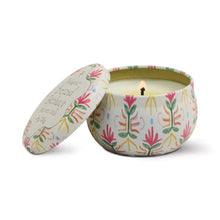 Load image into Gallery viewer, A lit Printed Tulip Candle Tin sits open, revealing its scented glow. The round tin features a decorative pink, green, and yellow floral pattern; the matching lid rests nearby.