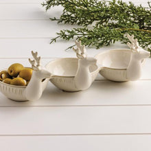 Load image into Gallery viewer, The Triple Deer Tidbit features three white ceramic dishes shaped like reindeer heads, arranged in a row. One holds green olives, while greenery and a white wood surface create a festive holiday setting.
