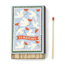 Load image into Gallery viewer, A Dopo 75ct Boxed Matches: a box of 75 safety matches with a decorative cover of white doves and red flowers on blue, reminiscent of Mediterranean travel. Includes one red-tipped match beside the box.
