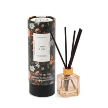 Load image into Gallery viewer, The Botanical Diffuser Set features a floral-patterned Cotton &amp; Teak tube beside a reed diffuser bottle with black sticks, providing an elegant way to enhance your home's fragrance.