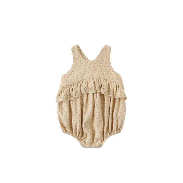 The Penny Romper - French Flora is a sleeveless beige baby romper made from soft organic cotton, featuring a subtle embroidered pattern and ruffled chest detail, shown on a white background.