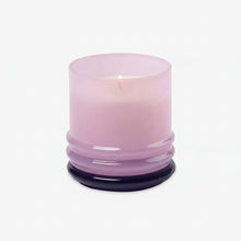 Load image into Gallery viewer, The 7oz Stacked Glass Candle features lit soy wax in a translucent light purple glass holder with a round, ridged base, displayed against a plain white background.