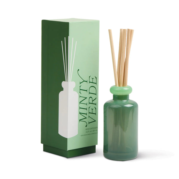 A green Stacked Reed Diffuser bottle with wooden reeds stands next to a matching Minty Verde box—ideal for infusing your home with refreshing fragrance.