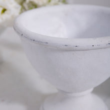 Load image into Gallery viewer, Close-up of the Rustic White Compote with a wide rim and pedestal base, ideal as a ceramic compote or floral arrangement vase. Blurred white flowers in the background enhance its serene, rustic charm.