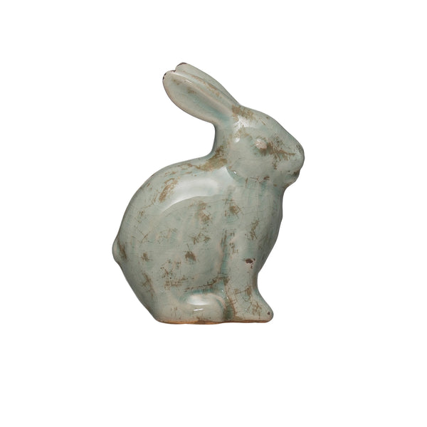 The Terracotta Rabbit is a small, weathered figurine with a light greenish-blue crackle glaze and rustic patches. Sitting upright on its hind legs, it makes perfect sculptural décor for any space.