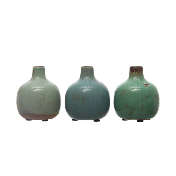 Three Terracotta Mini Vases with short necks in green and blue shades, featuring rustic finishes, evoke a charming vintage look and are displayed side by side on a white background.