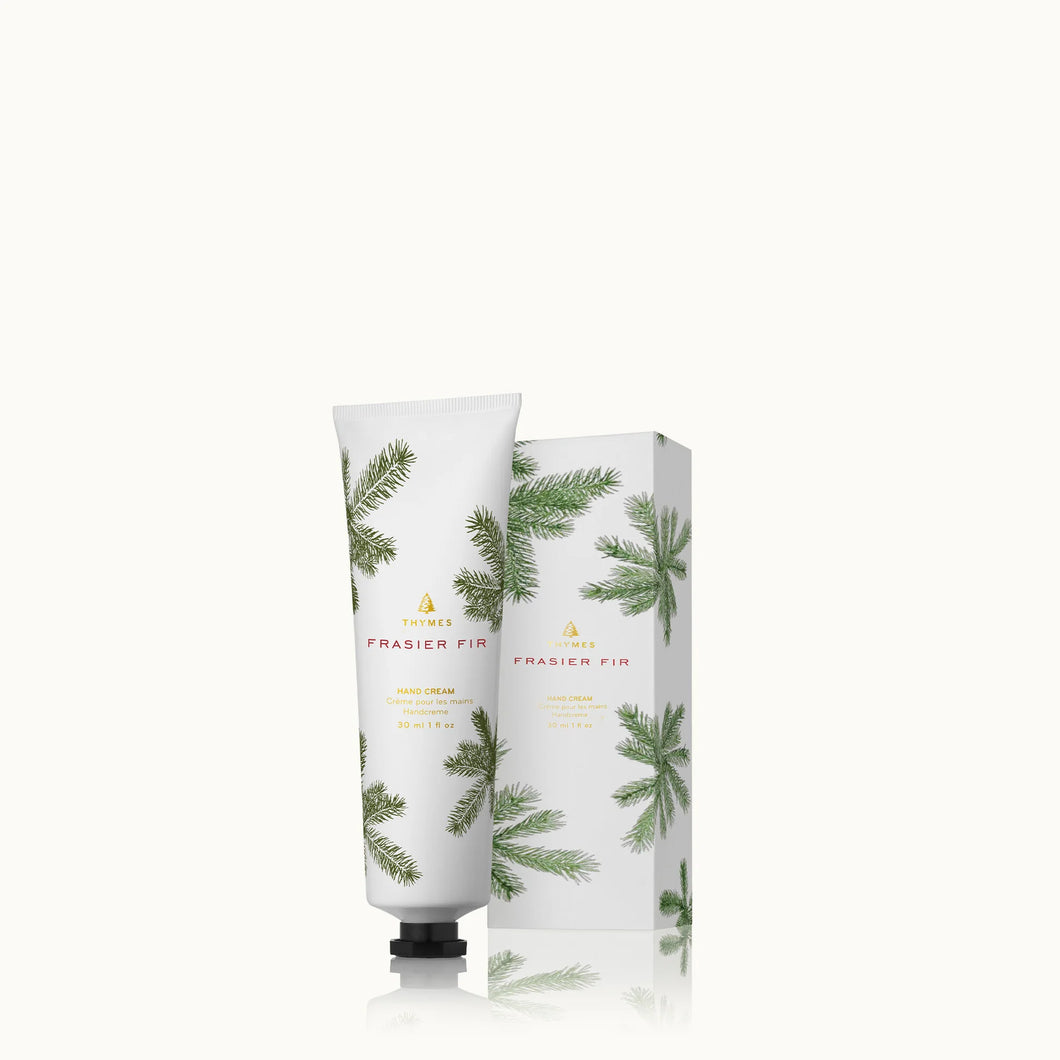 A white tube and matching box of Frasier Fir Home Care Collection hand cream, both featuring green pine branch designs, are displayed against a plain white background.