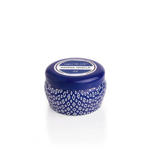 Load image into Gallery viewer, A small, round blue Capri Blue Mini Tin candle featuring a white geometric pattern and matching lid, labeled Havana Vanilla, sits on a plain white background, evoking the signature Capri Blue Jean collection style.