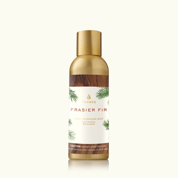 An upright gold and bronze Thymes Frasier Fir Home Care Collection fragrance mist can features pine branch artwork, offering a touch of winter to any room.