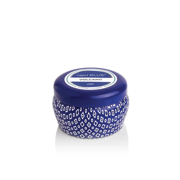 A small, round blue Capri Blue Mini Tin candle with a patterned design and matching lid features a label reading “capri BLUE VOLCANO.” The candle stands out against the plain white background.