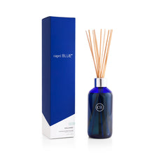 Load image into Gallery viewer, The Volcano Reed Diffuser features a blue glass bottle and several wooden reeds, packaged in a tall, stylish box—ideal for adding flameless fragrance and modern décor to your space.