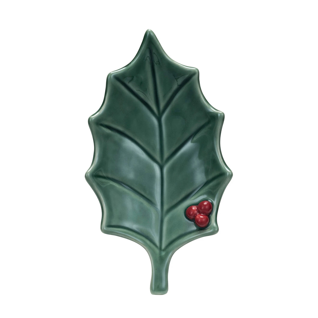 The Holly Leaf Dish is a handcrafted stoneware dish shaped like a green leaf with three red berries in one corner and a unique reactive glaze—perfect for festive or holiday use.