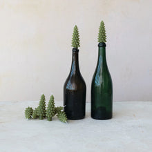 Load image into Gallery viewer, Two green wine bottles hold tree-shaped tapers from the Box/4 Shaped Candles set, with more grouped nearby, creating festive holiday décor against a plain pale background.