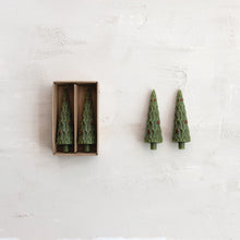 Load image into Gallery viewer, The S/2 Taper Tree Candles w/Holly—two green, unscented tree-shaped tapers with red holly decor—come in an open box and rest on a textured surface, adding festive charm to your holiday décor.