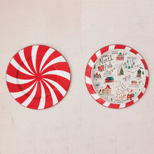 Load image into Gallery viewer, Two round plates on a light surface: the left has red and white peppermint swirls, while the right is the North Pole Plate featuring colorful holiday stoneware illustrations and seasonal designs.