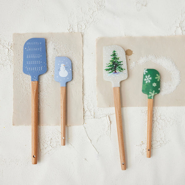 The S/2 Spatulas set includes two holiday kitchen utensils with wooden handles, featuring festive winter designs and a blue silicone spatula with a convenient conversion chart.